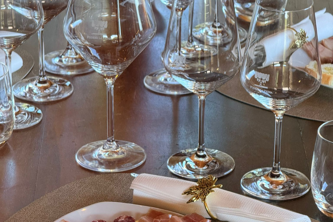 Calici di vino rosso e tagliere di salumi e formaggi durante una degustazione a Podere la Vigna